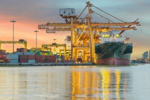 Industrial Container Cargo freight ship with working crane bridge in shipyard at dusk for Logistic Import Export background